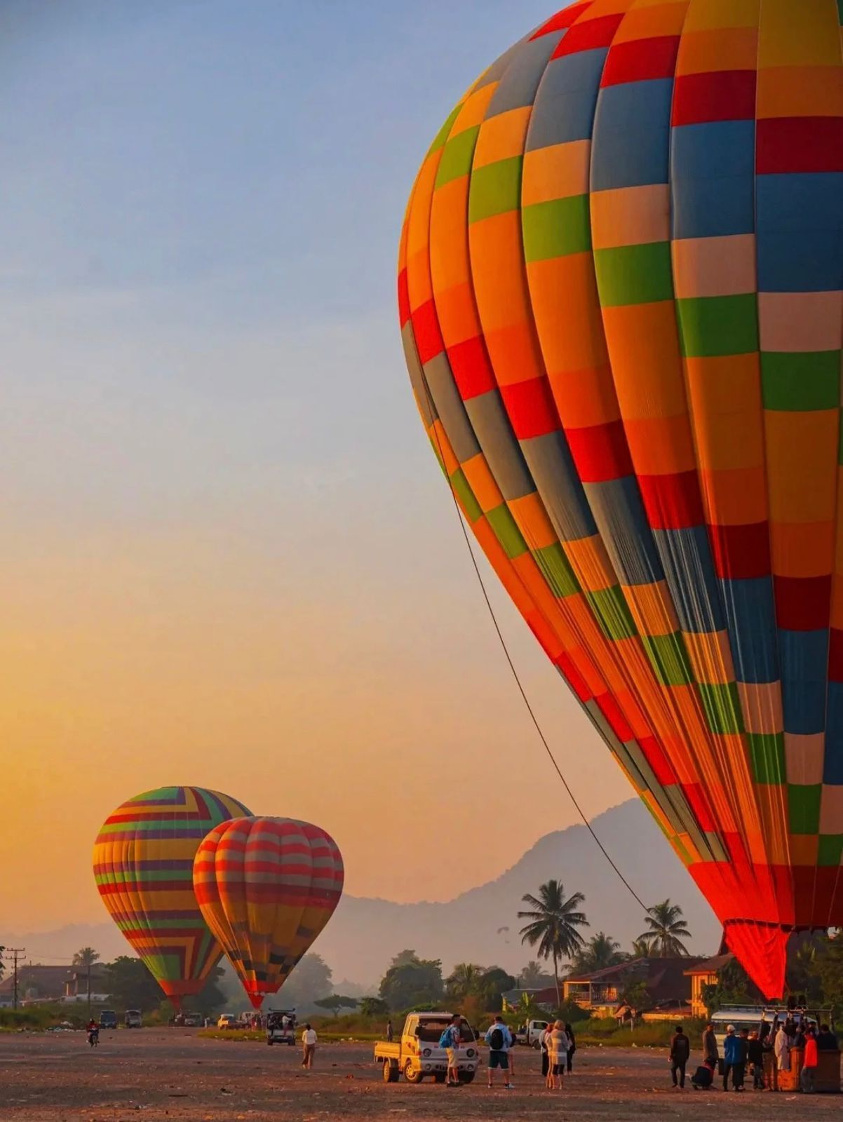 A hot air balloon festival with colorful balloons, a truck, and people gathered on the ground.