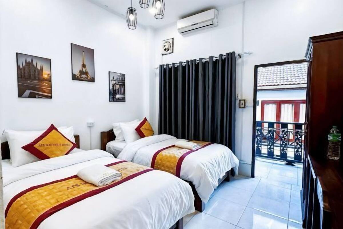 A hotel room with two beds, a view of the street, and a balcony.