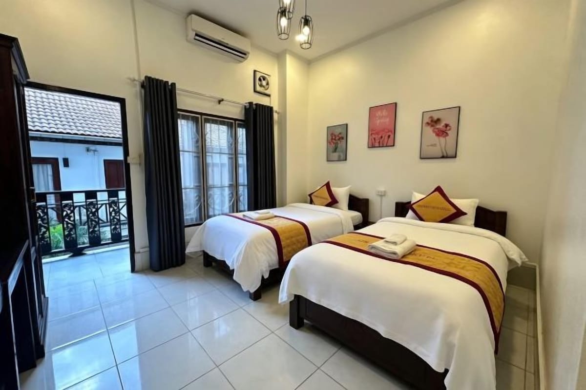 Habitación de hotel con dos camas, un balcón y vistas al exterior.