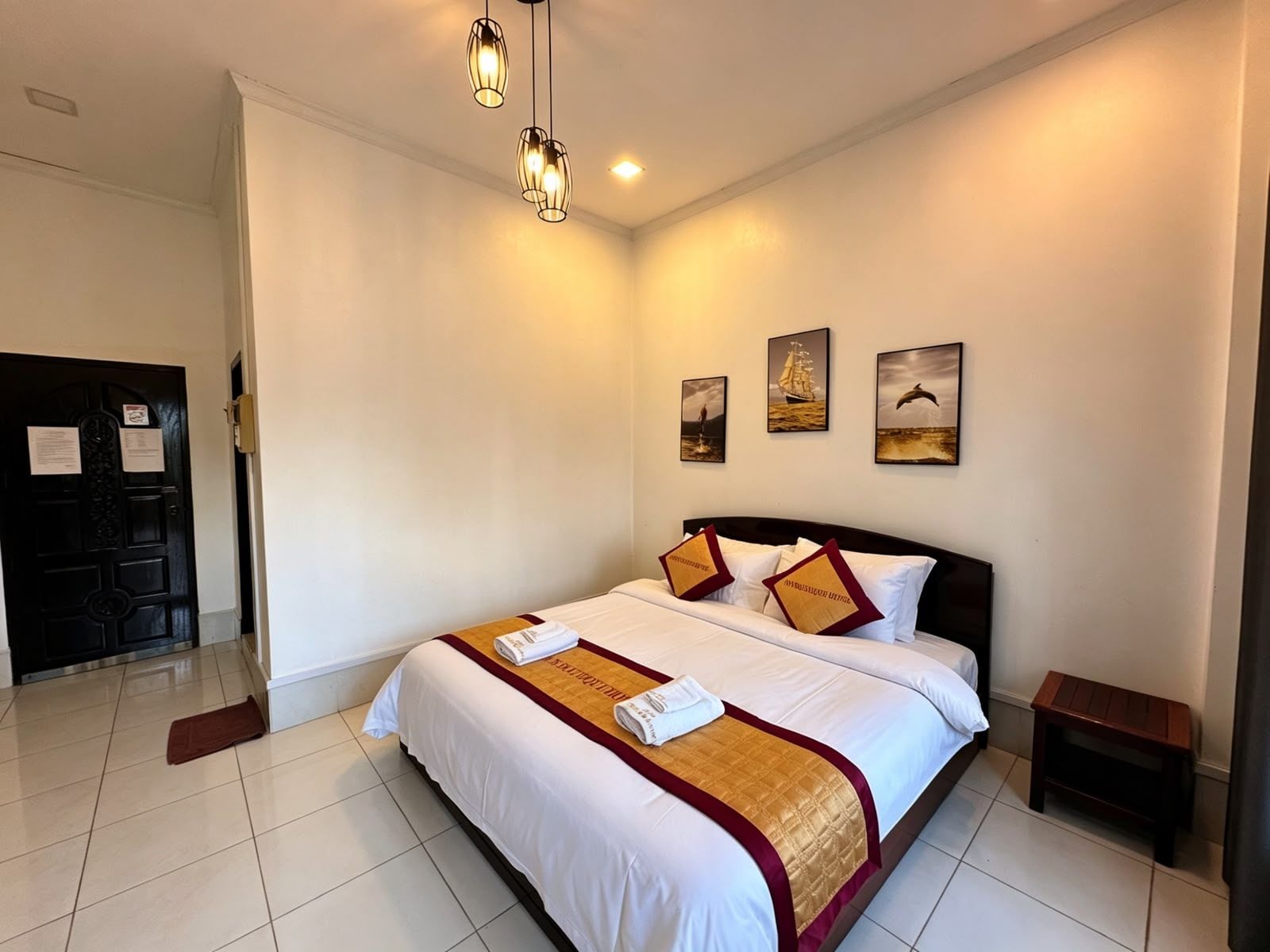 Una habitación de hotel con una cama grande, una mesita de noche pequeña y una puerta con un cartel.