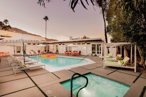 A pool area with lounge chairs and umbrellas, surrounded by a building with a covered patio and a mountain in the background. - 3 Private 1 Bedroom Units at The Wesley Sleeps 12 (Palm Springs)
