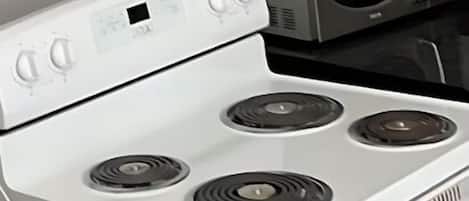 A kitchen with a white stove, a microwave, and dark wooden cabinets.