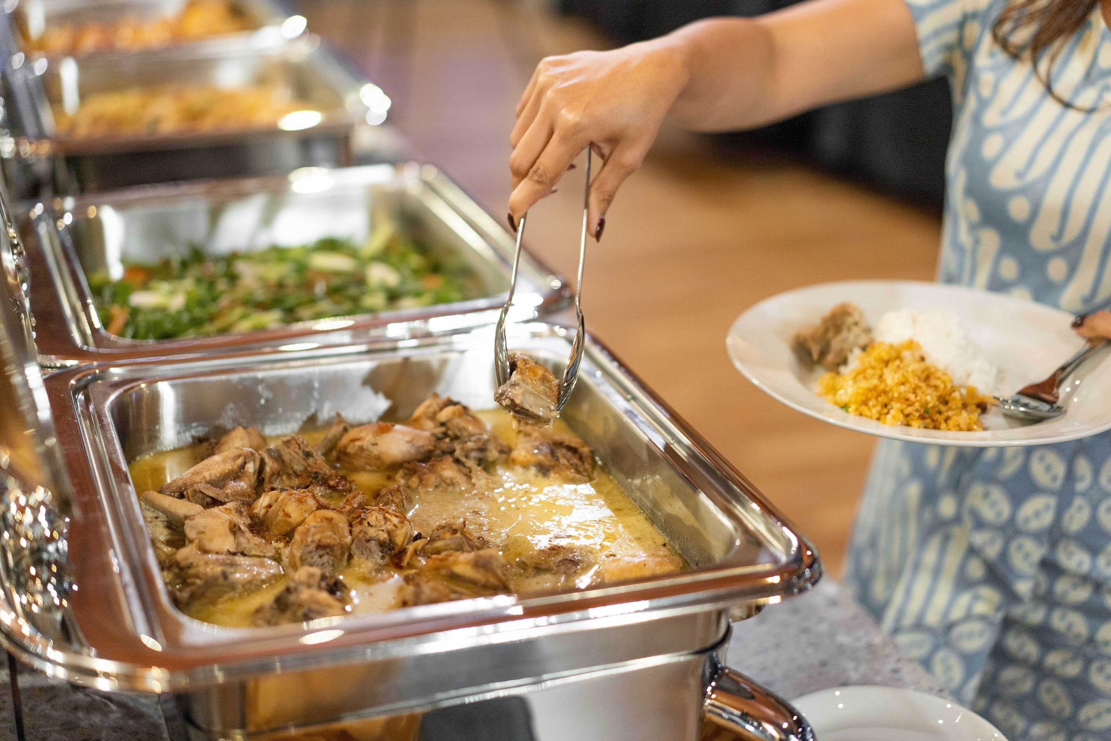 A buffet with various dishes, including a dish with meat and a dish with greens.