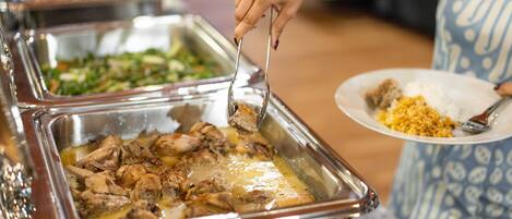 A buffet with various dishes, including a dish with meat and a dish with greens.