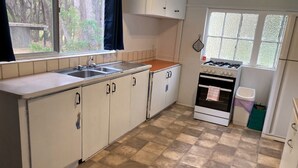 Een keuken met een gasfornuis, spoelbak en kastjes.