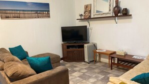 Een woonkamer met een bank, een televisie, een bijzettafeltje en een radiator.