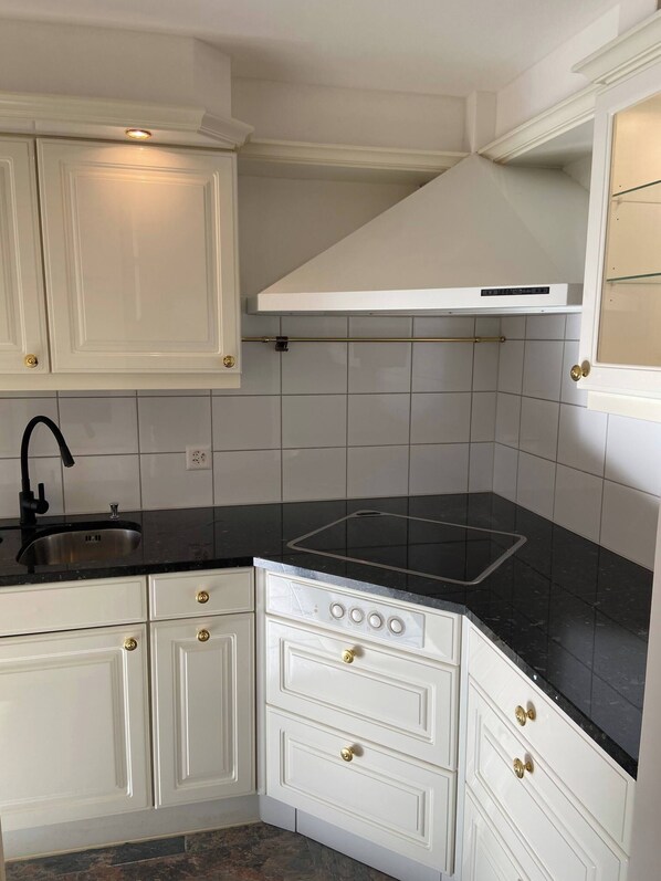 A kitchen with white cabinets, a black countertop, a stainless steel sink, and a gas stove. - In the Green but in 20 Minutes in Basel (Ettingen)