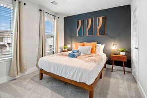Une chambre à coucher avec un lit, des tables de chevet et des œuvres d’art accrochées au mur.