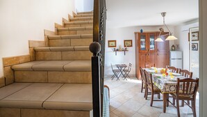 A staircase leading to a dining area with a table set for two, wooden cabinets, and a refrigerator. - Casa Machiavelli Near The Sea, Porto Cesareo, Italy (Porto Cesareo)