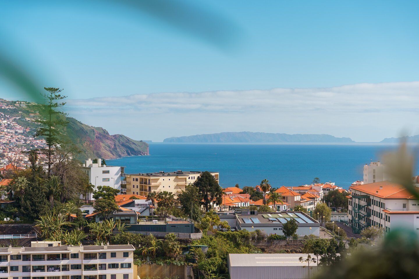 A coastal town with buildings, a view of the sea, and a hilly landscape.
