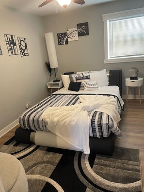 A bedroom with a bed, bedside tables, a floor lamp, and artwork on the walls.