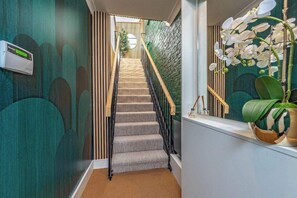 Staircase with a carpeted landing, adorned with a potted orchid and a small table.