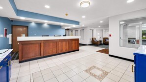 A reception area with a wooden counter, white walls, and blue accents. - LakeWood Inn & Suites (Dowagiac)