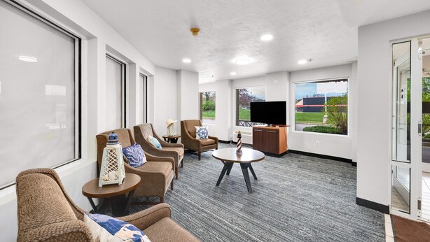 A spacious lobby with a seating area, a television, and large windows offering a view of the outdoors. - LakeWood Inn & Suites (Dowagiac)