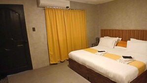 A hotel room with a large bed, a wooden headboard, a yellow curtain, and a small table with a chair. - Hotel O Annexe Rest House (Kuantan)