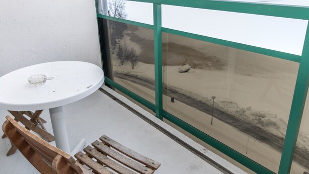 A balcony with a white table and a wooden bench, overlooking a snowy landscape.