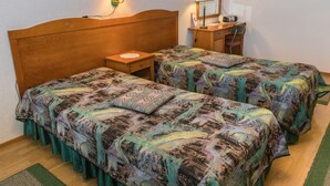 A room with two beds, a nightstand, a mirror, and a radio.