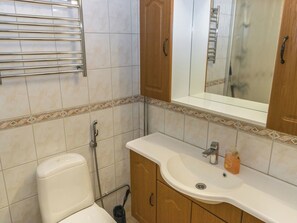 A bathroom with a toilet, a sink, a mirror, and a shower. - Hotelli terme, huone 312 by Interhome (Ikaalinen)
