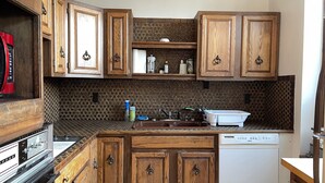 A kitchen with wooden cabinets, a built-in stove, a dishwasher, and a patterned backsplash. - Loft w/Amazing Deck in Historic Downtown Laramie (Laramie)