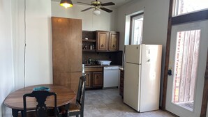 A compact kitchen with wooden cabinets, a white refrigerator, a dining table with chairs, and a ceiling fan. - Loft w/Amazing Deck in Historic Downtown Laramie (Laramie)