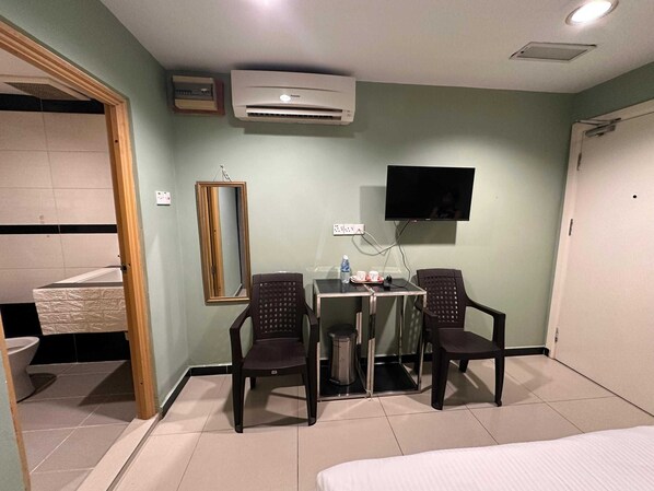 A hotel room with a bed, a desk with two chairs, a TV, an air conditioner, a mirror, and a bathroom visible through an open door. - Hotel O Rainfield Inn (Kota Kinabalu)