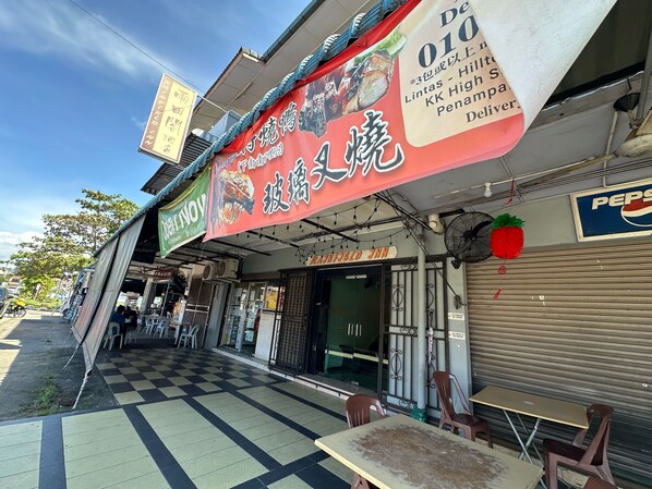 Une vue de rue d’un restaurant appelé « NNN », avec un sol à carreaux et des tables en terrasse.