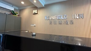 En receptionsdisk med et moderne design, komplet med et skilt for 'Rainfield Inn' og en dekorativ plantetilpasning.