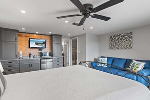 A bedroom with a bed, a ceiling fan, a TV, a kitchenette, and a blue sofa. - Private beach access, Gulf Views, on-site golf car (Santa Rosa Beach)