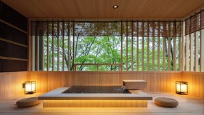 A wooden spa area with a hot tub, two wall-mounted lights, and a view of trees through bamboo blinds. - Nazuna Hakone Miyanoshita (Hakone)