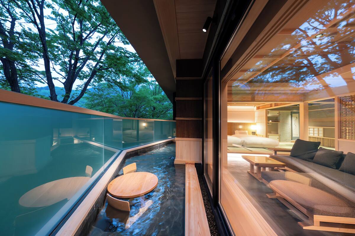 A modern spa area with a hot spring, wooden furniture, and a view of trees.