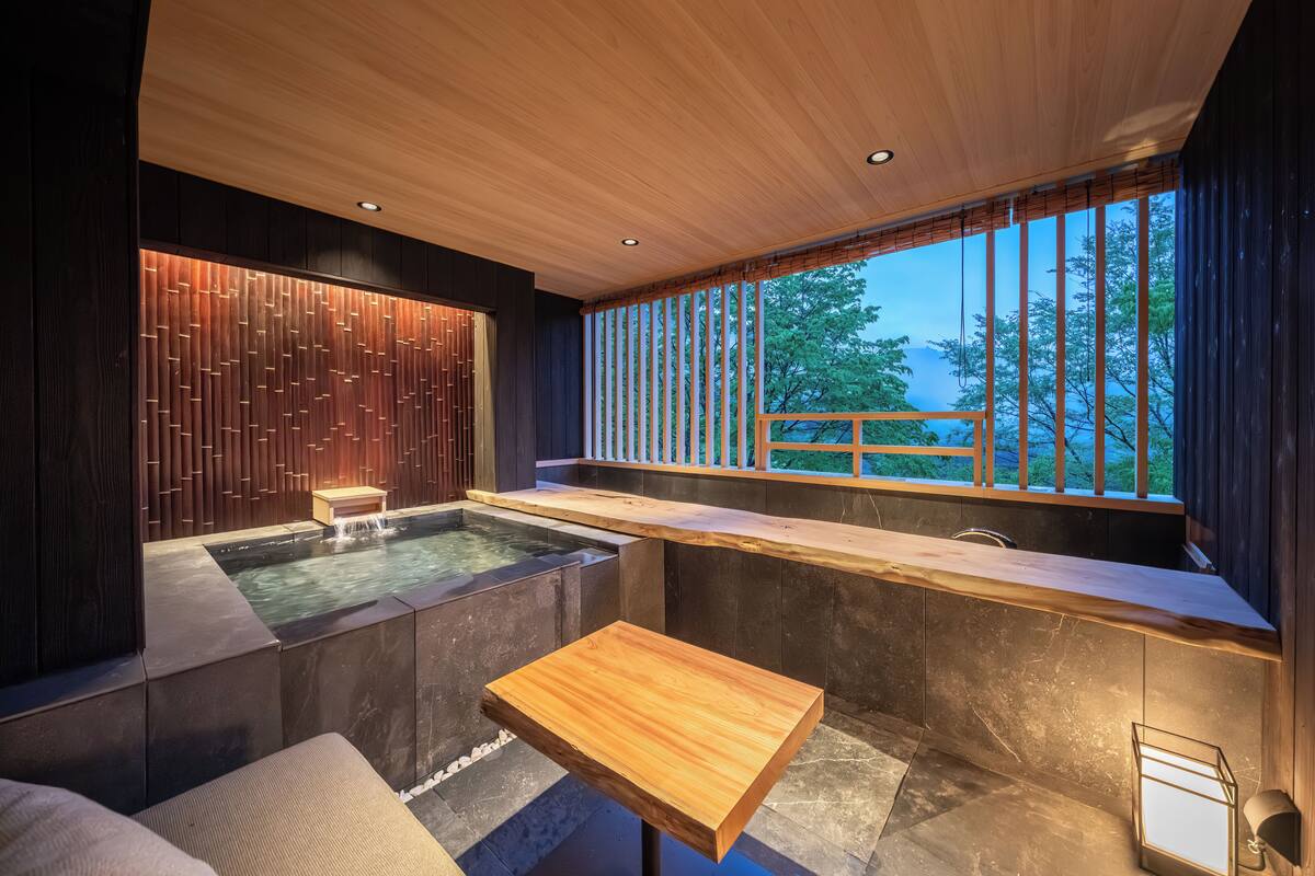 A modern spa area with a wooden ceiling, a hot tub, and a wooden table.