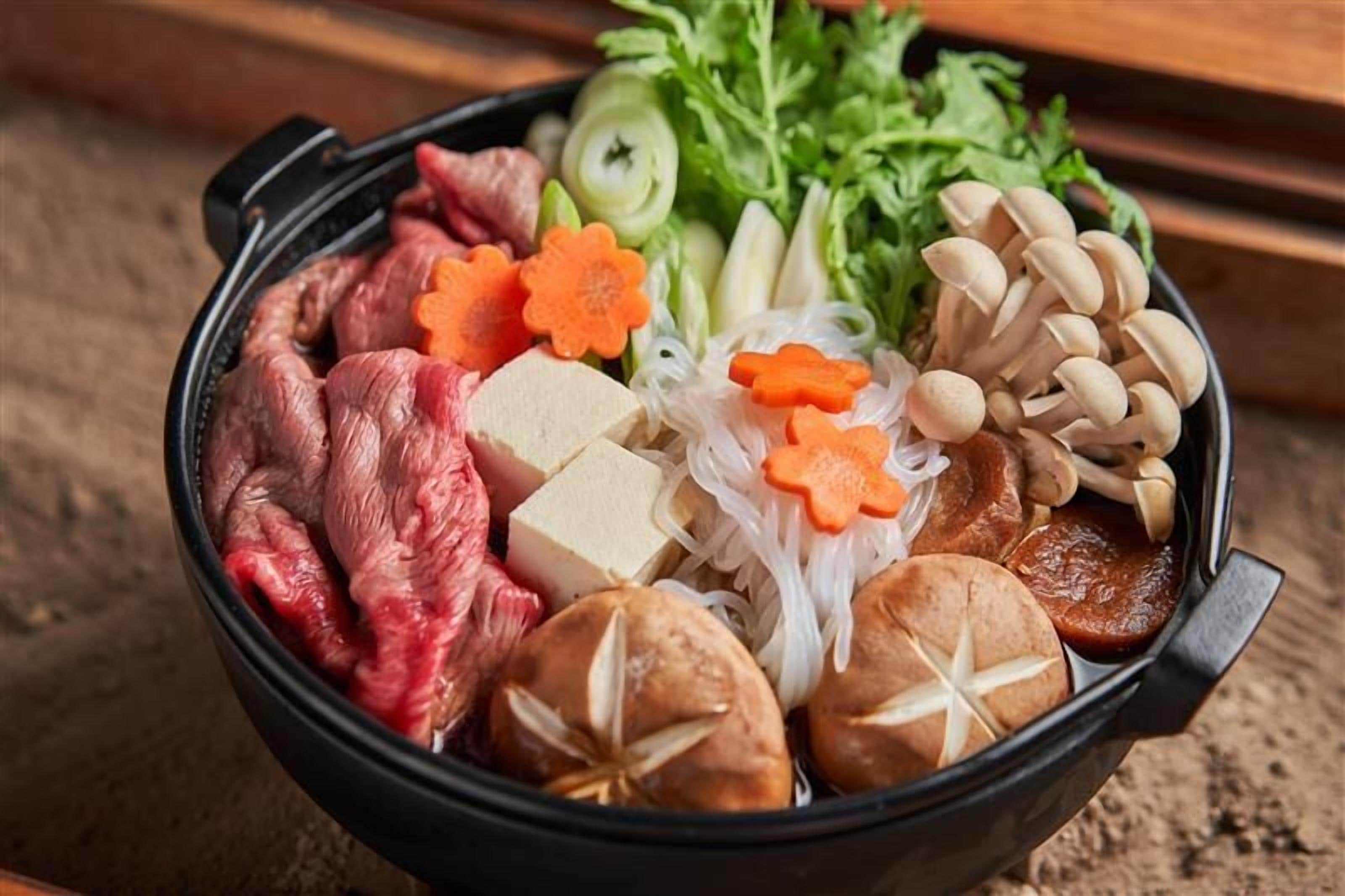 Un bol contenant un assortiment d’aliments, notamment de la viande, du tofu, des champignons et des légumes.