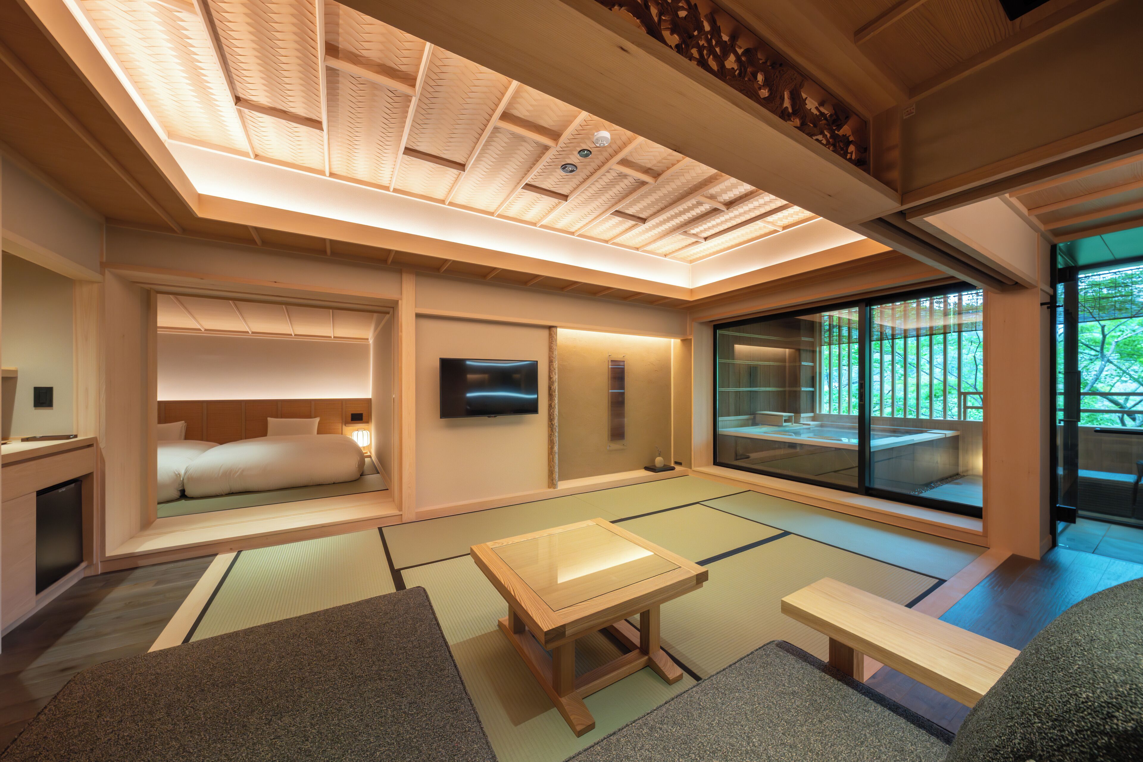 A traditional Japanese room with tatami flooring, a low wooden table, a bed, and a sliding glass door to a garden.