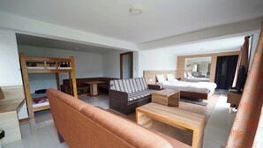 Ett modernt hotellrum med en våningssäng, en soffa, ett soffbord och en säng med en sänggavel.
