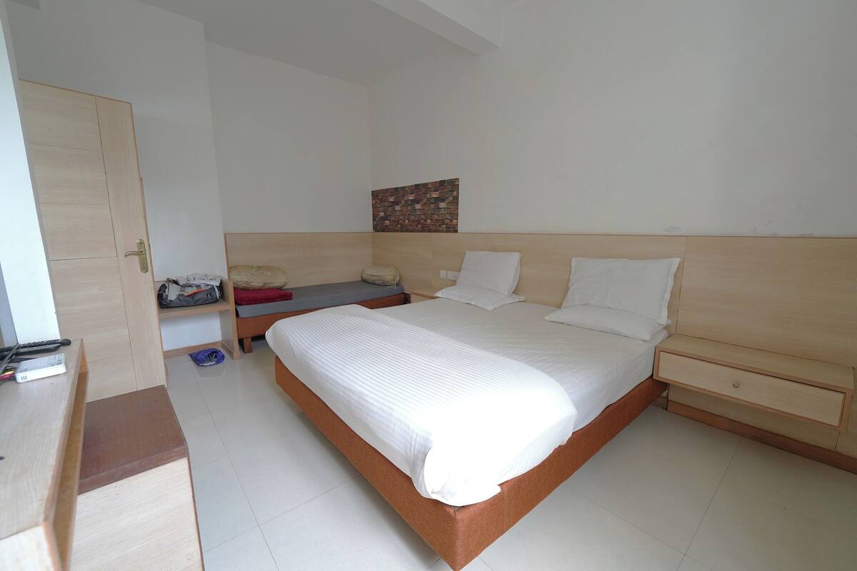 A bedroom with a wooden bed, a nightstand, a wardrobe, and a small table with a chair.