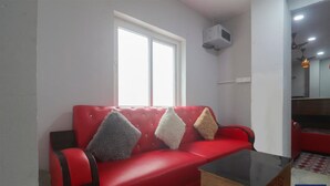 En röd soffa med ett svart bord framför sig, ett fönster och en takfläkt.