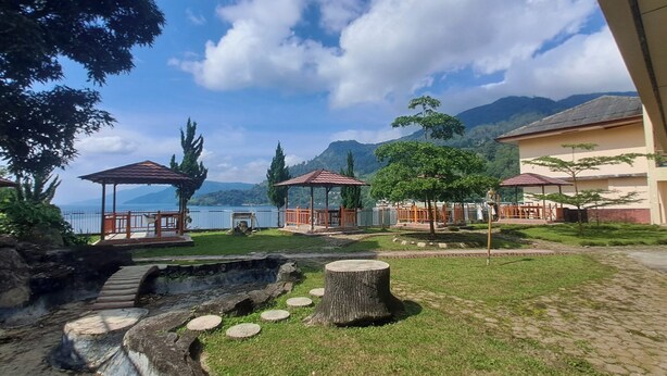 Un'area esterna tranquilla con un gazebo, un vialetto in pietra e vista sul lago e sulle montagne.