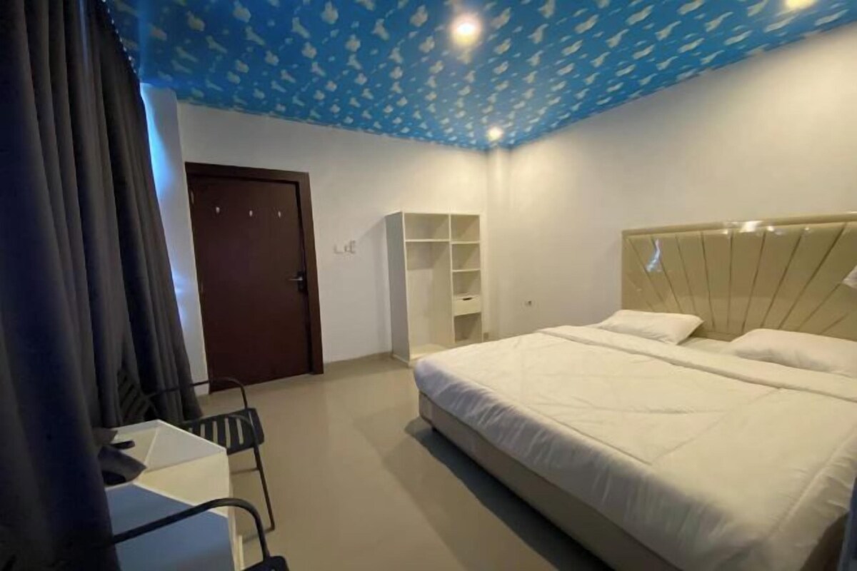 Un dormitorio con cama, escritorio, armario y puerta.