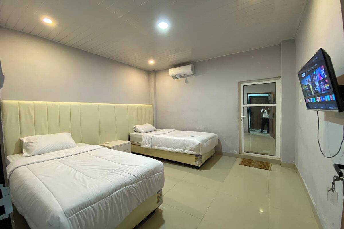 A hotel room with two beds, a television, and an air conditioning unit.