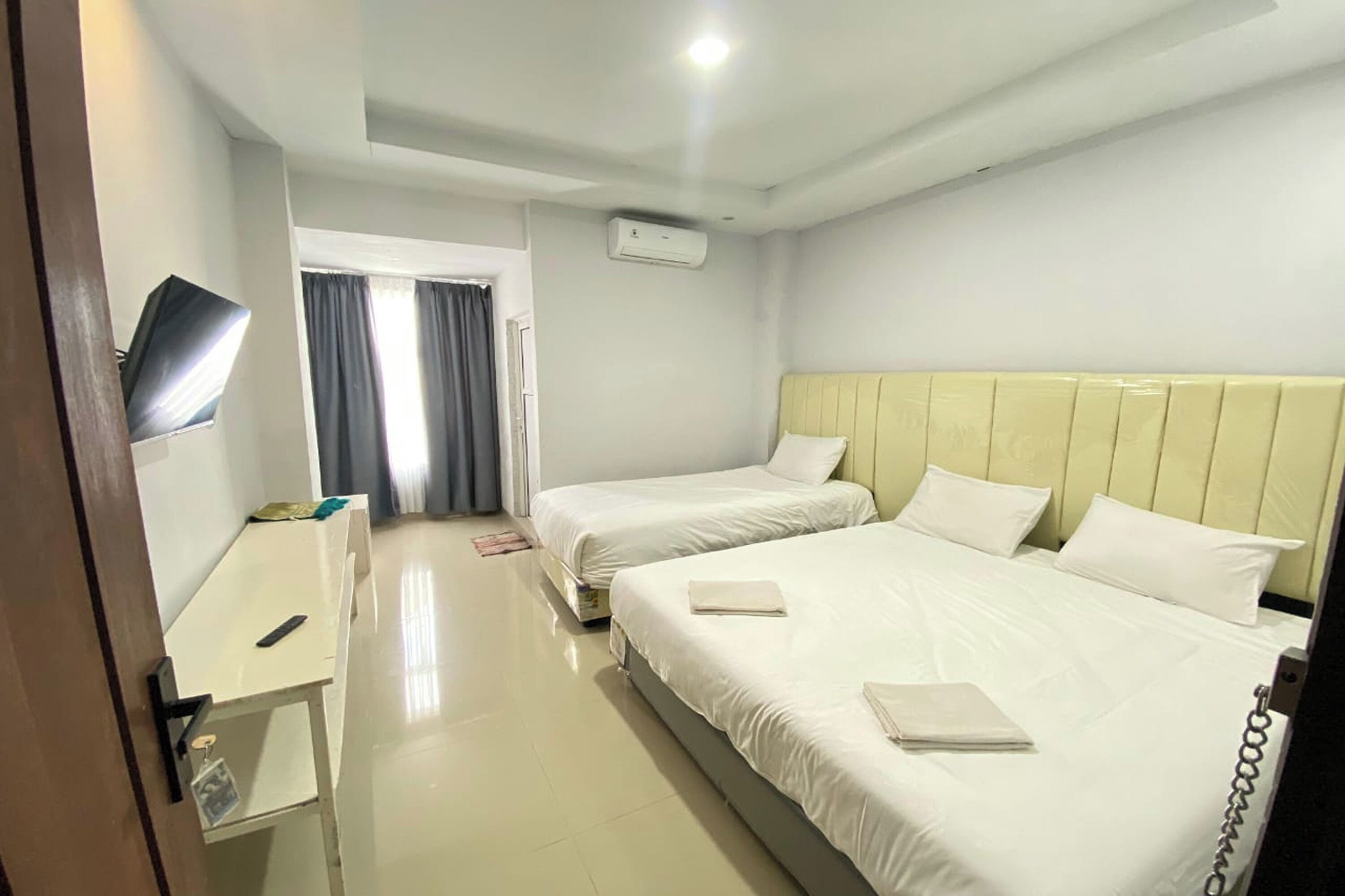Une chambre d’hôtel avec deux lits, un bureau, une télévision et un appareil de climatisation.