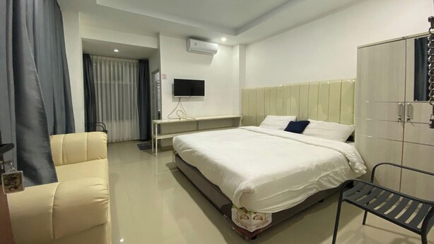 A modern hotel room with a large bed, a bedside table, a TV, and a wardrobe. - Ranls Dream Syari'Ah Banda Aceh (Banda Aceh)