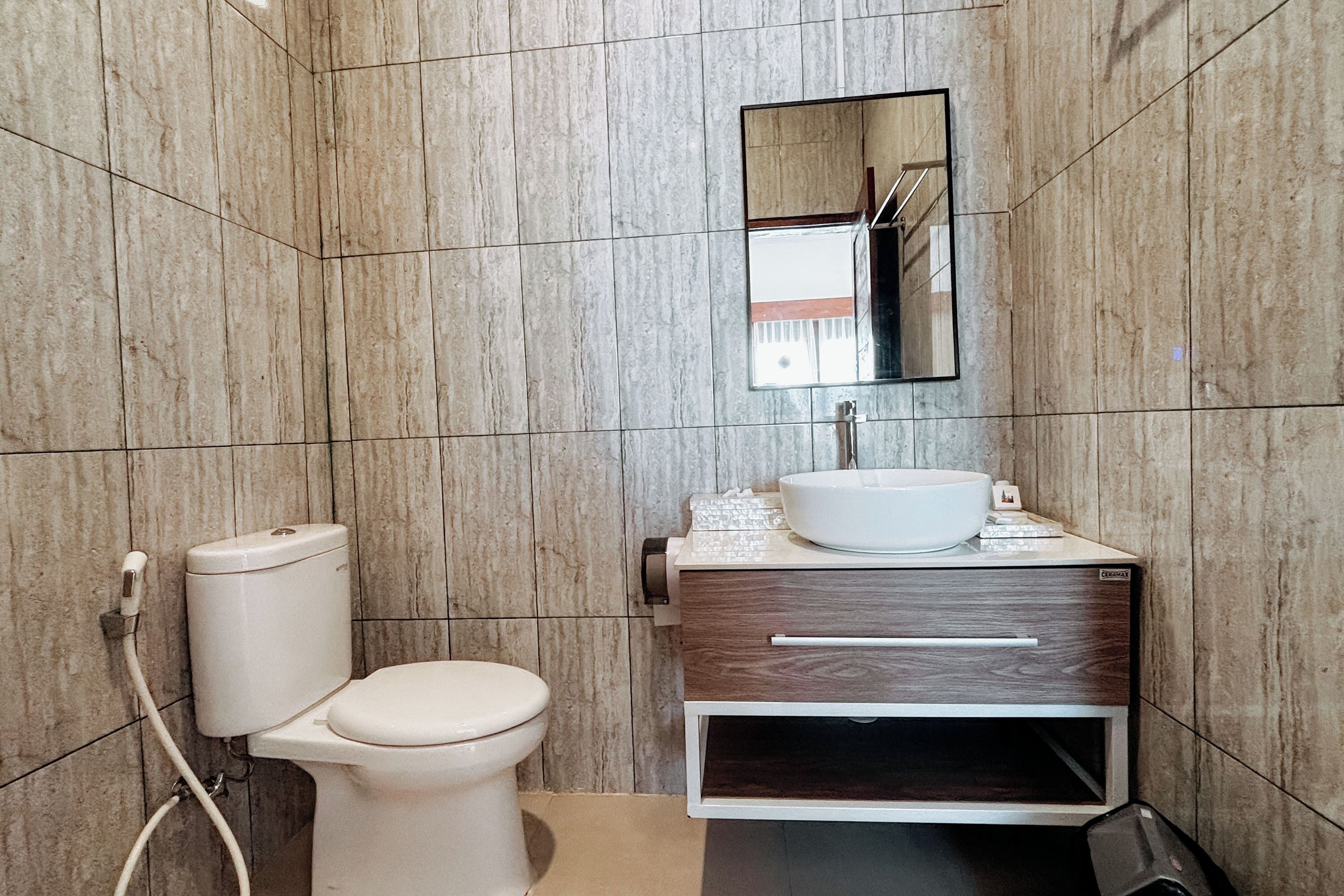 Une salle de bain avec des toilettes, un lavabo et un miroir.