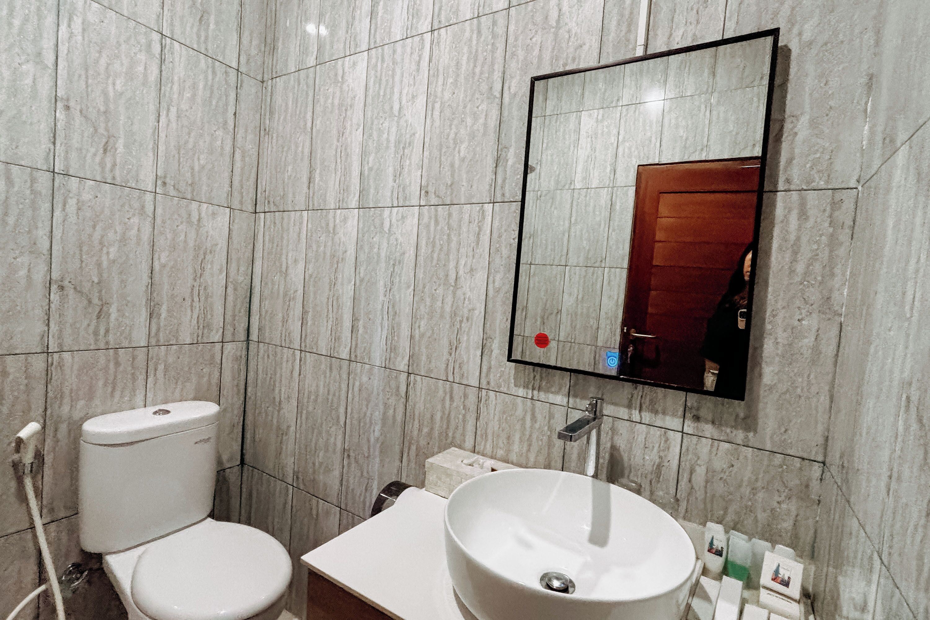 Een badkamer met toilet, wastafel en spiegel.