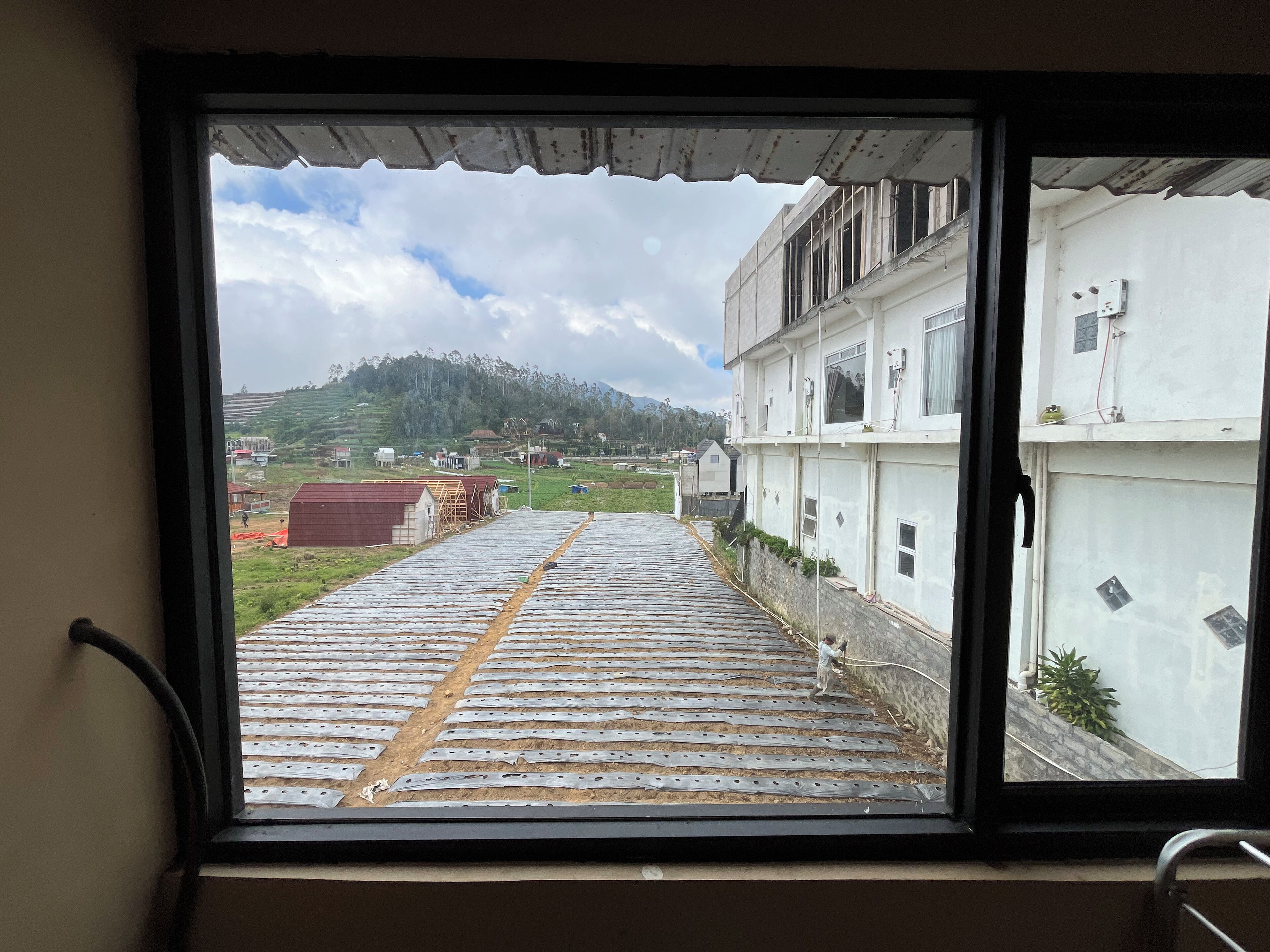 A view through a window of a building with a sloped roof and a person working on the exterior wall.