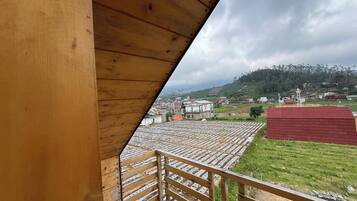 Blick von einem Holzbalkon auf gestufte Felder und ein Dorf.