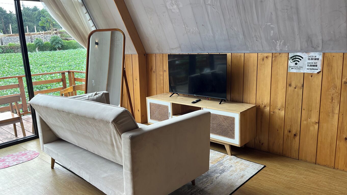 Una habitación con sofá, televisión y pared de madera.