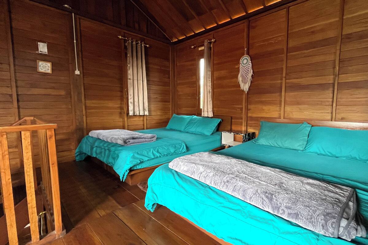 A cabin with two beds, wooden walls, and a small wooden table.
