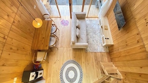 A wooden interior with a sofa, a table, and a patterned rug. - Fifa Cabin Dieng By Fifa Grup (Dieng Kulon)