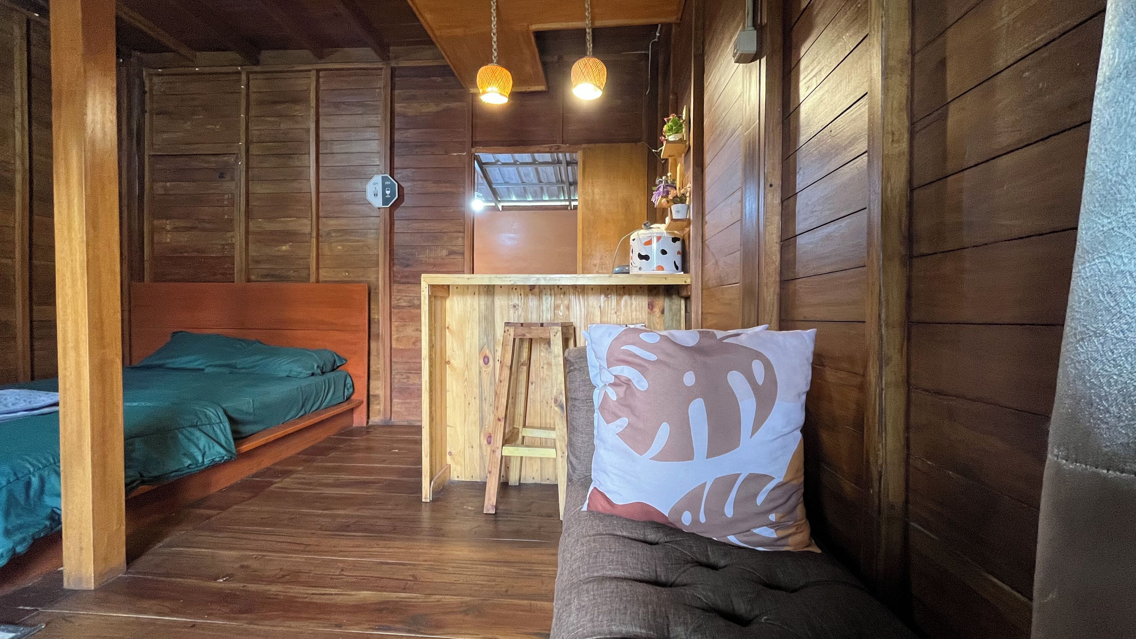 A wooden cabin room with a bed, a small desk, and a chair.
