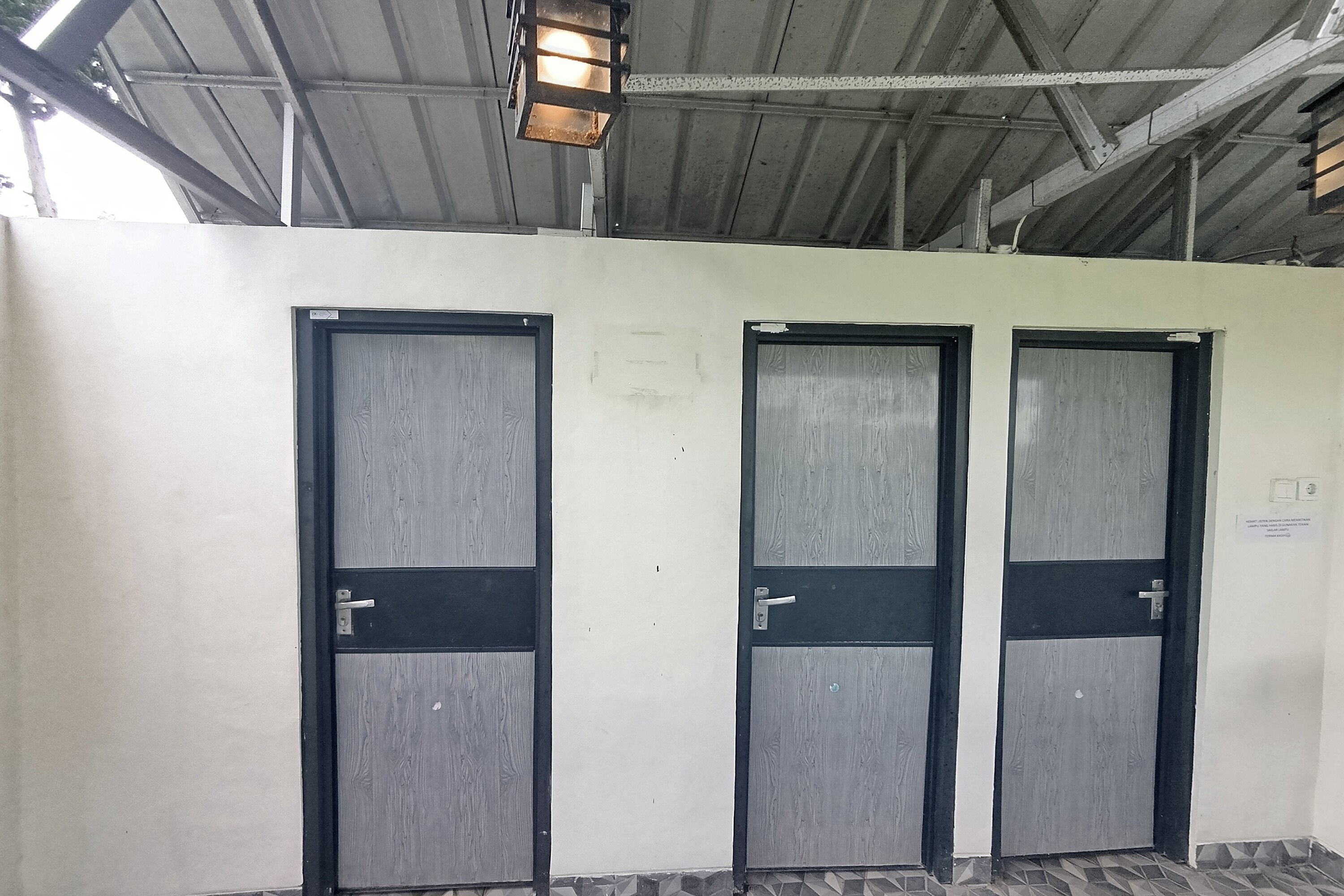 Tre porte con stipiti in metallo e vetri, un soffitto metallico e un pavimento piastrellato.